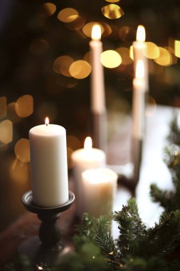 Şampanya bardakları ahşap masada, mumlar bulanık duvarda ve Noel ağacında.