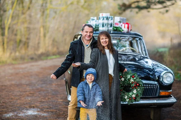 穿着保暖衣服笑着的成年男女站在古董车旁 带着圣诞礼物 — 图库照片