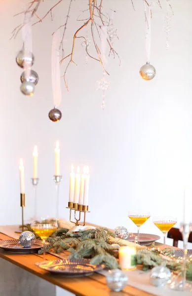 クリスマスの装飾とぼやけた壁に対するろうそくと木製のテーブルの上にシャンパングラス — ストック写真