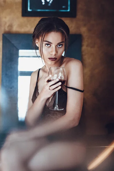 Linda jovem mista raça em lingerie sedutora segurando copo de vinho tinto . — Fotografia de Stock