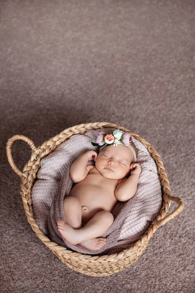 Schattig pasgeboren baby meisje dragen bloem hoofdband slaapt in mand. — Stockfoto