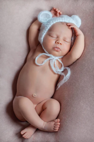 かぎ針編みの白いクマのボンネットを着た10日の生まれたばかりの女の子は、ピンクの毛布の上で平和に眠ります. — ストック写真