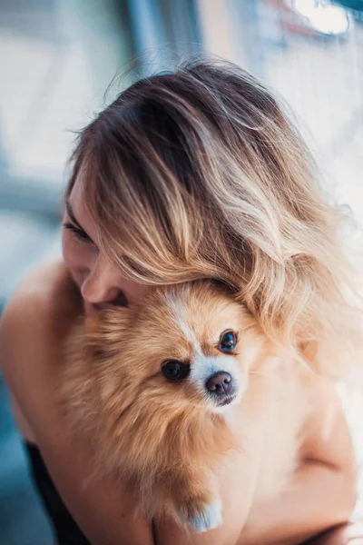 Close-up portret van glimlachende jonge aantrekkelijke vrouw omarmen Pomeranian spitz. — Stockfoto