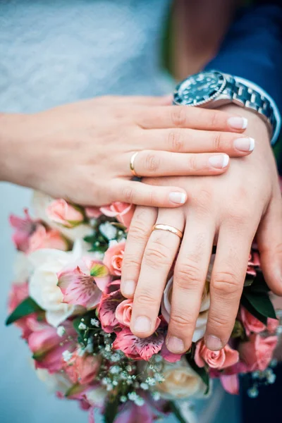 Foto de cerca de las manos de la novia y el novio con anillos de boda y ramo de flores . — Foto de Stock