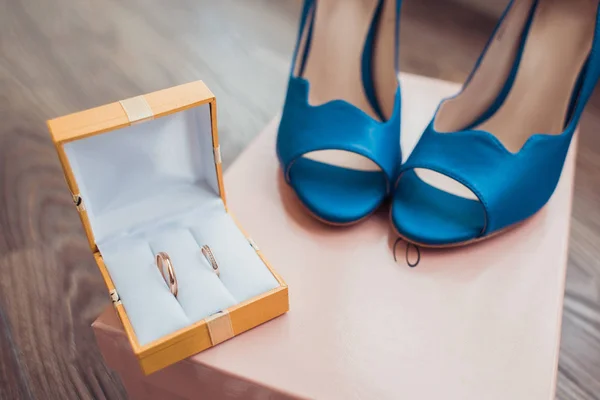 Bridal morning details composition: wedding rings and blue leather shoes. — Stock Photo, Image