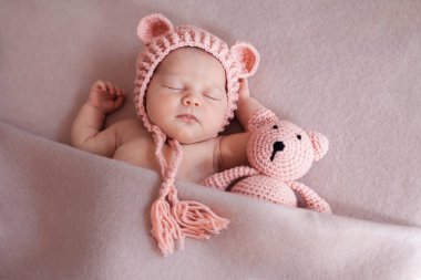 Sevimli yeni doğmuş bebek kız oyuncak ayıyla yatıyor..