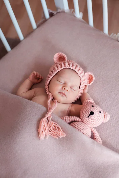 Schönes neugeborenes Mädchen trägt rosa Hut und schläft friedlich in ihrem Bett. — Stockfoto