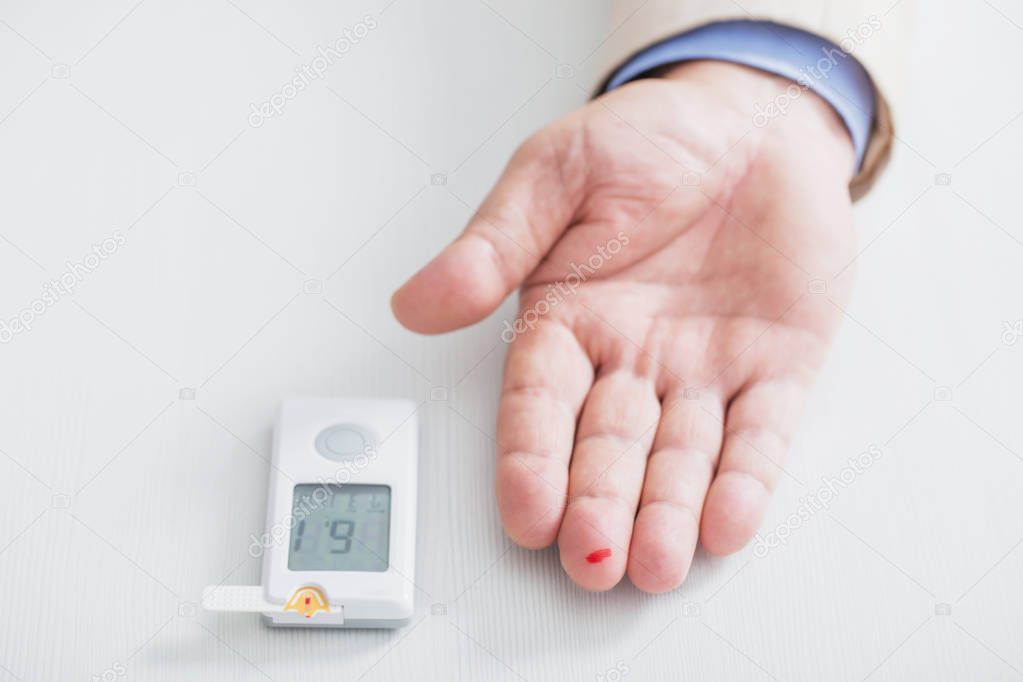 man measures sugar level with a glucometer