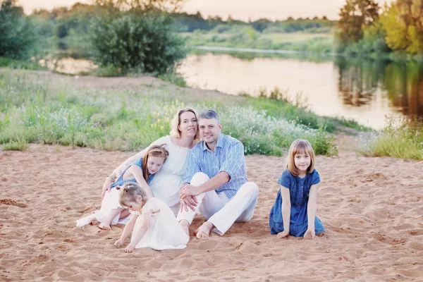 happy family sitting on sand by river