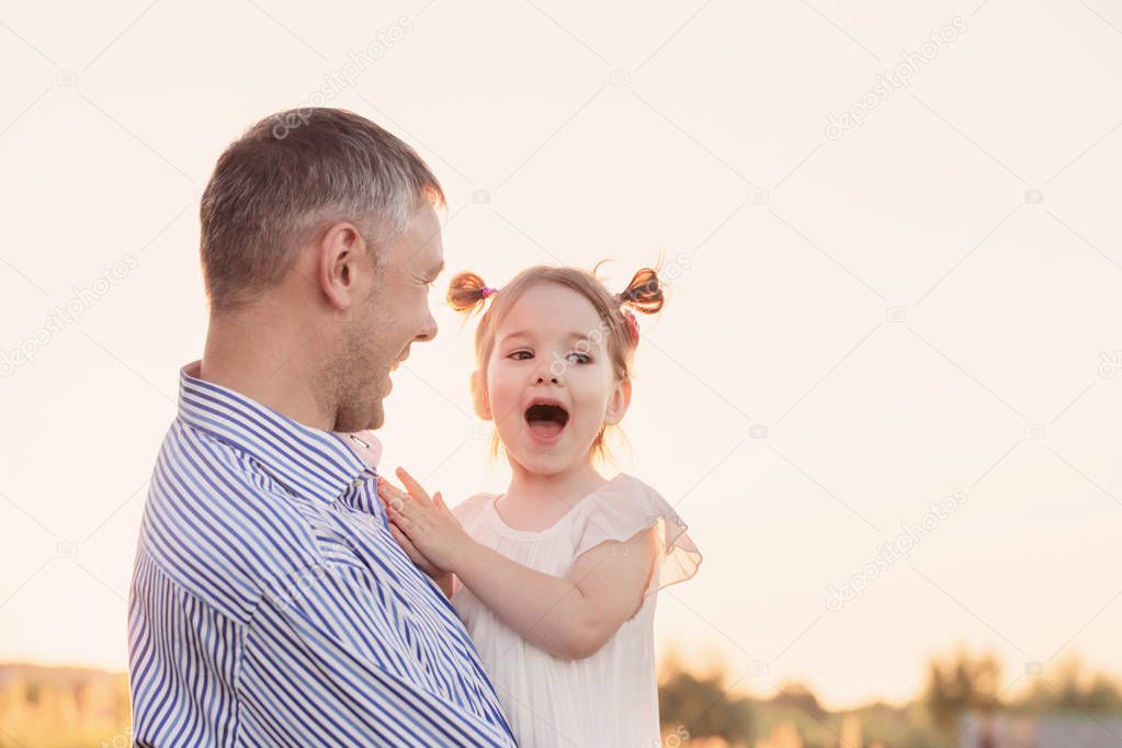 father with daughter on background sunset sky