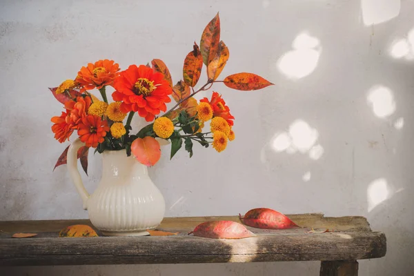 古い木製のベンチにピッチャーに秋の花 — ストック写真