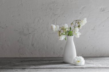 Eski arka plan üzerinde vazoda beyaz güller