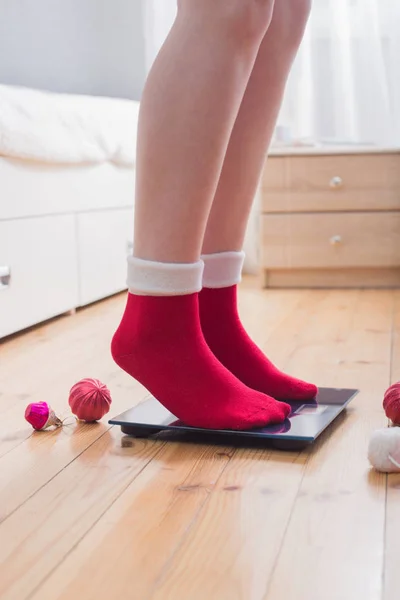 クリスマスの飾りと赤い靴下で体重管理のための電子秤の上に立って女性の足 — ストック写真
