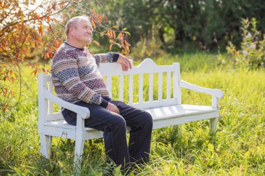 Sonbahar Park beyaz tahta bankta oturan yaşlı adam