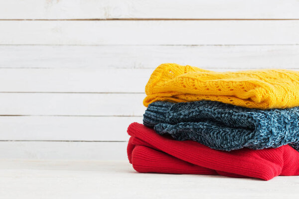knitted sweaters on white wooden background