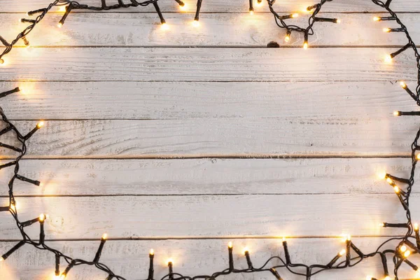 Christmas lights on painted white wooden background