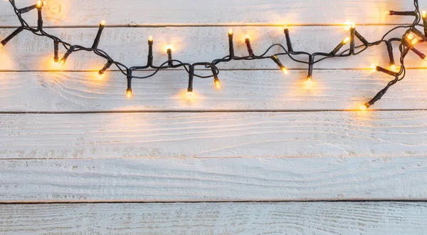 Christmas lights on painted white wooden background