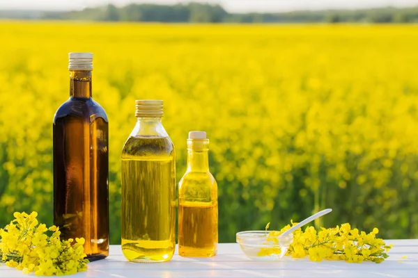 rapeseed oil in field on white wooden table