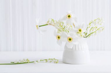 Beyaz ahşap arka planda vazoda bahar çiçekleri