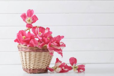 Beyaz ahşap zemin üzerinde sepette pembe laleler