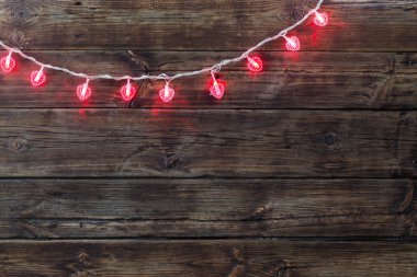 Eski koyu ahşap arka plan üzerinde kırmızı kalp şeklinde garland