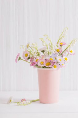 Beyaz ahşap arka planda vazoda bahar çiçekleri