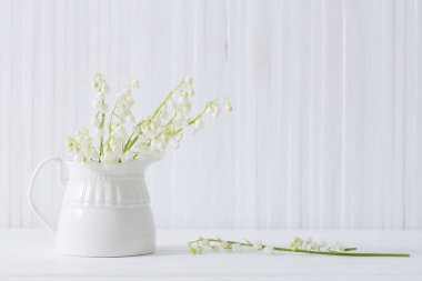 Beyaz ahşap arka planda vazoda bahar çiçekleri