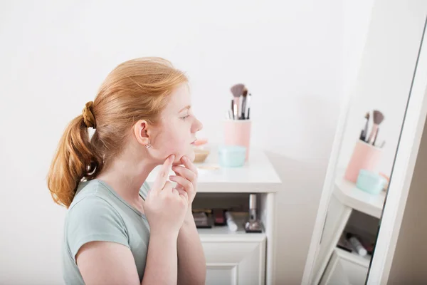 10代の女の子は鏡の前でにきびを調べる — ストック写真