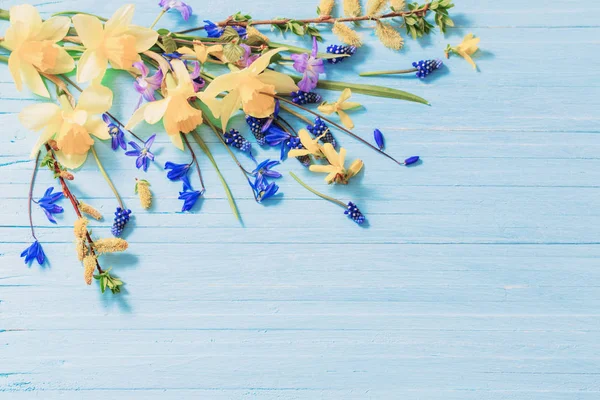 ahşap zemin üzerine sarı ve mavi bahar çiçekleri
