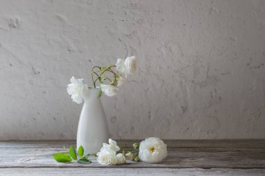 Eski arka plan üzerinde vazoda beyaz güller