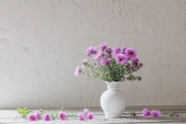 古い白い背景の上に白い花瓶に紫の花 — ストック写真