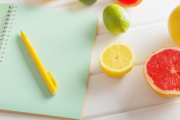 citrus with notebook on white wooden table