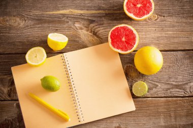 eski ahşap masa üstünde defter ile narenciye