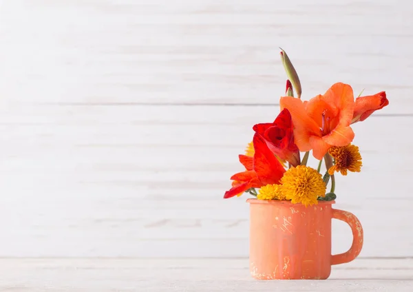 木桌上的橙色旧杯子里的花朵 — 图库照片