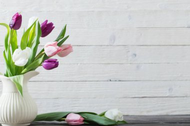 Beyaz ahşap zemin üzerinde beyaz vazoda bahar çiçekleri