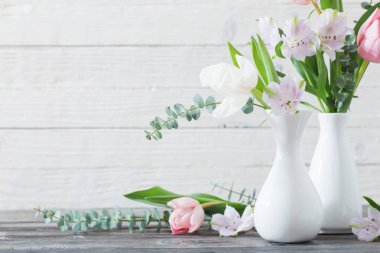Beyaz ahşap zemin üzerinde beyaz vazoda bahar çiçekleri