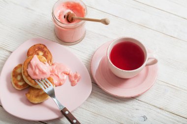 çay ve Beyaz ahşap masa üzerinde pembe meyve ballı krep