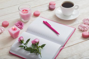 Beyaz ahşap masada kahve fincanı olan defter.