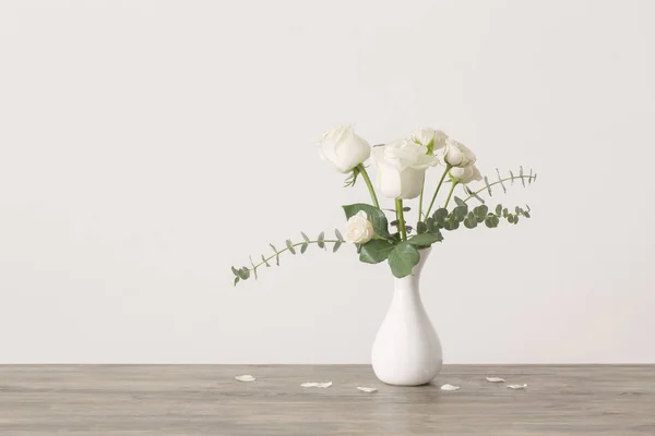 Brindilles d'eucalyptus et roses en vase sur fond blanc — Photo