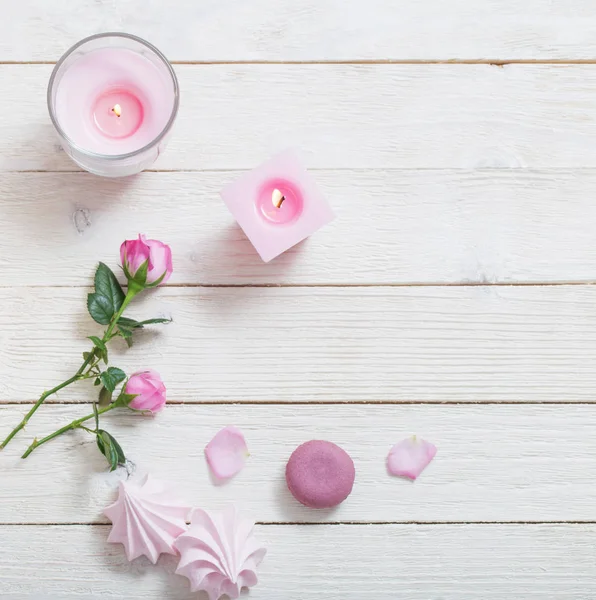 candles and roses on white wooden background