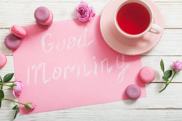 Tazza di tè e amaretti rosa sul tavolo di legno bianco — Foto Stock