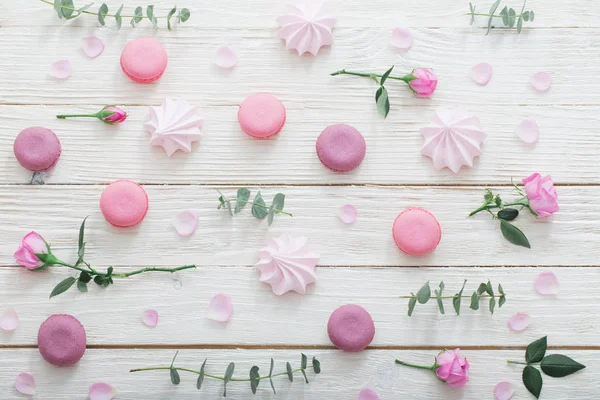 Fondo bianco in legno con fiori rosa, amaretti e foglie — Foto Stock