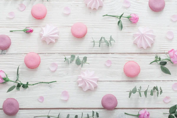 Weißer Holzhintergrund mit rosa Blüten, Makronen und Blättern — Stockfoto