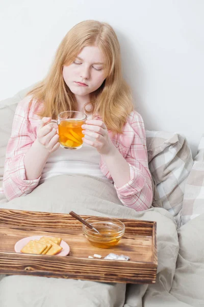 Nemocná dívka s šálkem čaje s citronem a zázvorem — Stock fotografie