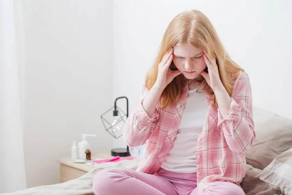 Tiener meisje met hoofdpijn in slaapkamer — Stockfoto