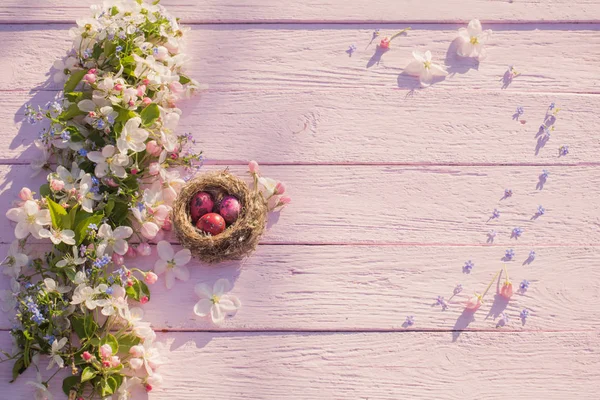 Wielkanocne jaja w gnieździe na różowym tle drewnianych — Zdjęcie stockowe