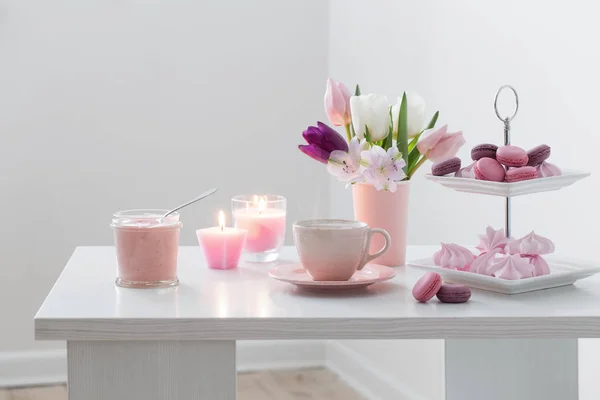 Tulpaner i vas och kopp kaffe med dessert på vita bak — Stockfoto