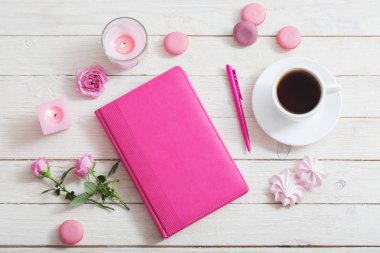 Beyaz ahşap masada kahve fincanı olan defter.