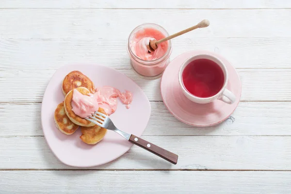 Thé et crêpes aux fruits roses miel sur table en bois blanc — Photo