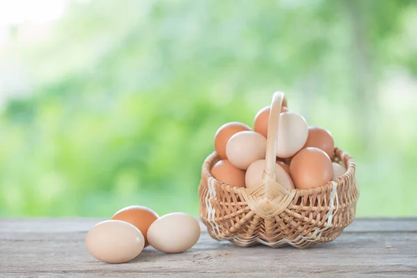 Raw eggs in basket on wooden table outdoor — Stock Photo, Image